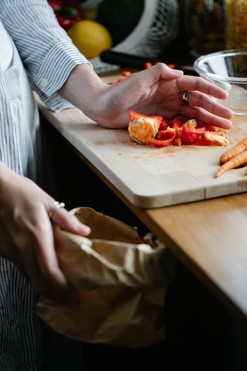 Vegetable leftovers being scraped together on a chopping board