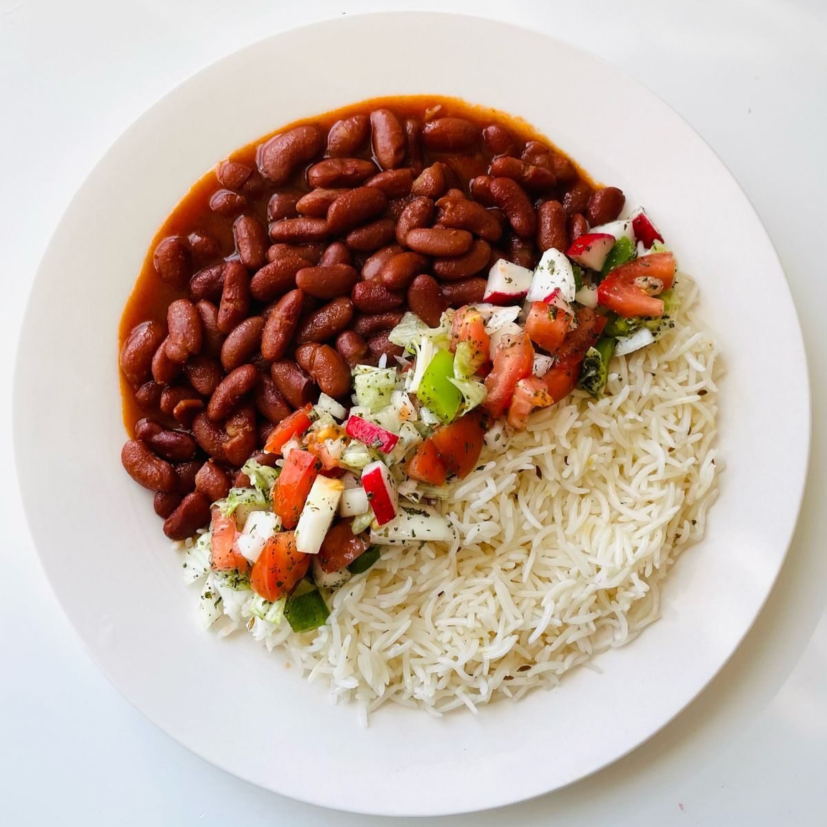 Cooked rice with tomatoes and beans on a white plate